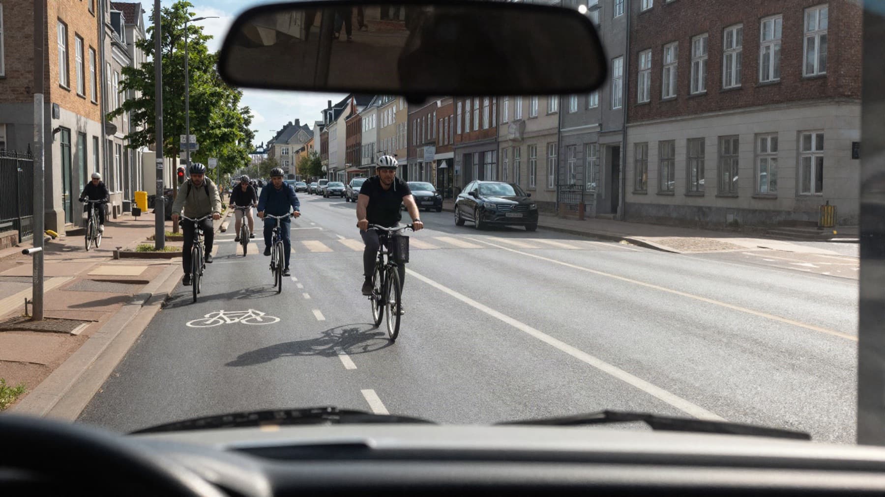 Set fra førersædet: cyklister på cykelstien og trafik på en københavnsk gade.